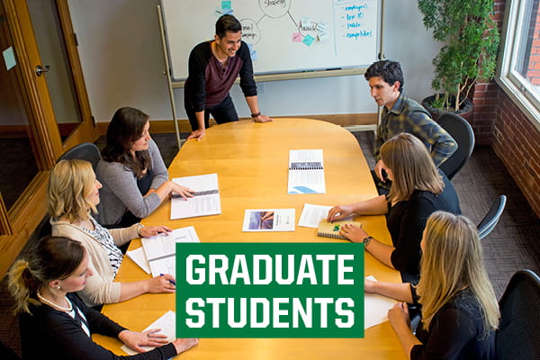 Image of graduate students working at a conference table with the text "Graduate Students"
