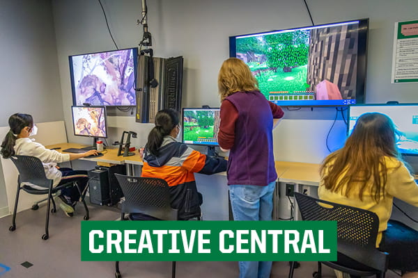 Image of staff person guiding three students using computers with the text "Creative Central"